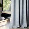 Close-up of FLEUR curtain fabric showing fine embroidered floral patterns on light blue textured fabric, highlighting premium quality and soft draping.
