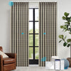 Patterned electric curtains in a room with a brown armchair and a plant.